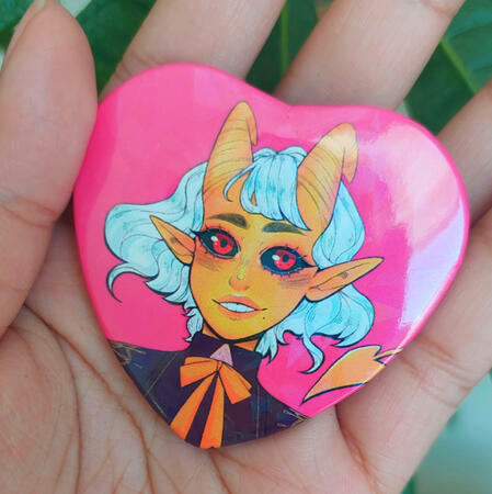 Heart Button Heart shaped button in hot pink with a yellow tiefling girl smiling